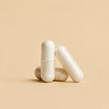 Three white veggie capsules on a beige background